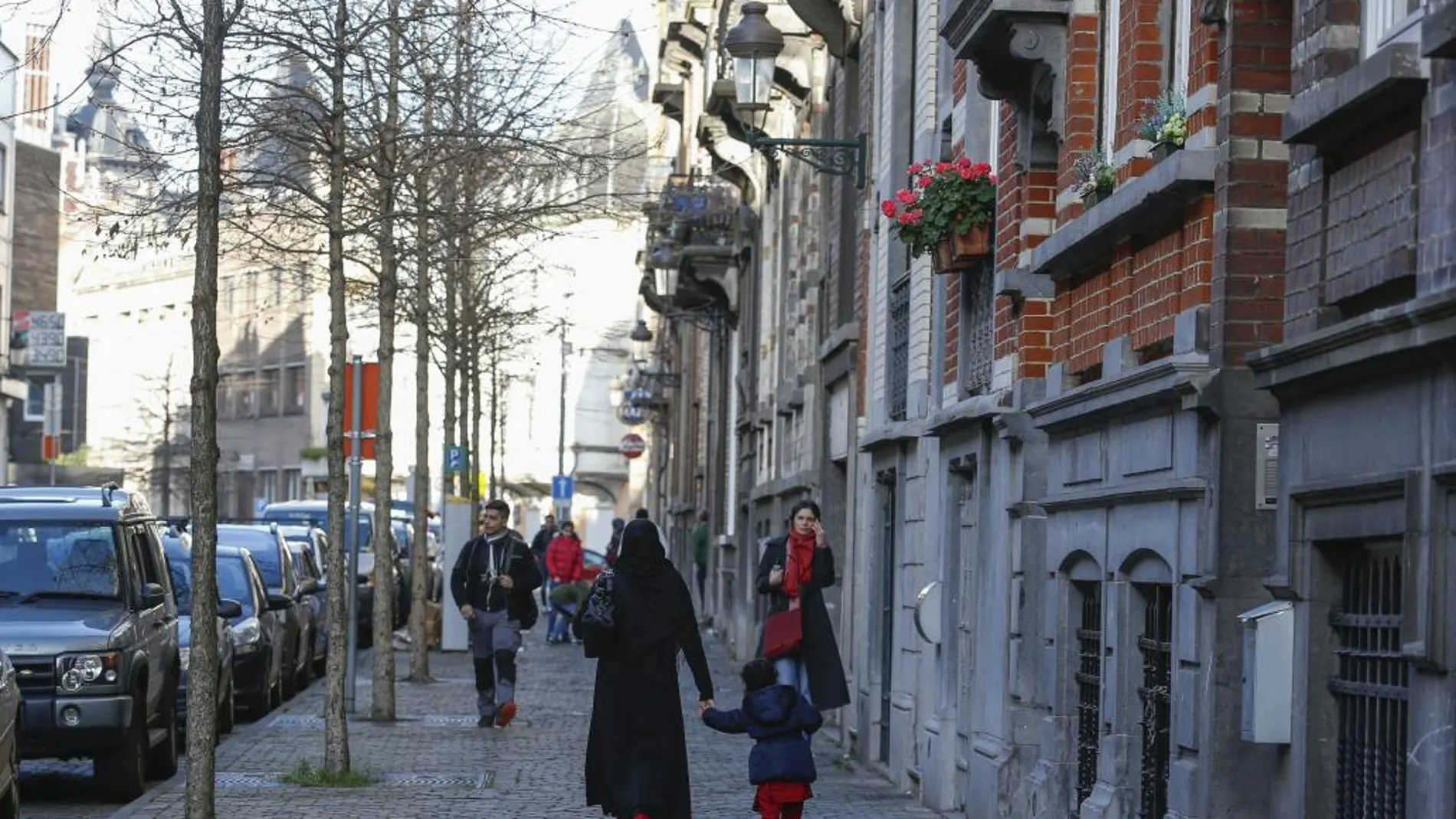 Peatones transitan por barrio de Schaerbeek, donde la Fiscalía ha confirmado el hallazgo en un apartamento de rastros de explosivos y tres cinturones como los utilizados en París.