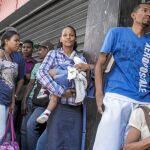 Yeniré Morales hace cola con una de sus hijas en brazos para comprar arroz en uno de los establecimientos de Caracas