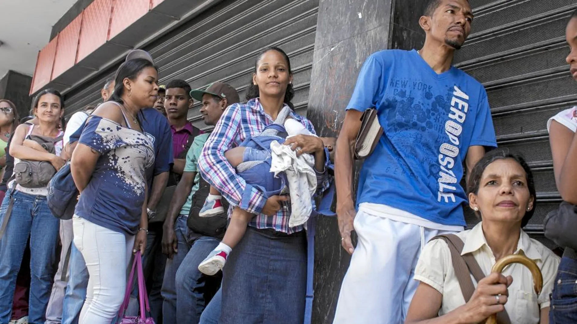Yeniré Morales hace cola con una de sus hijas en brazos para comprar arroz en uno de los establecimientos de Caracas