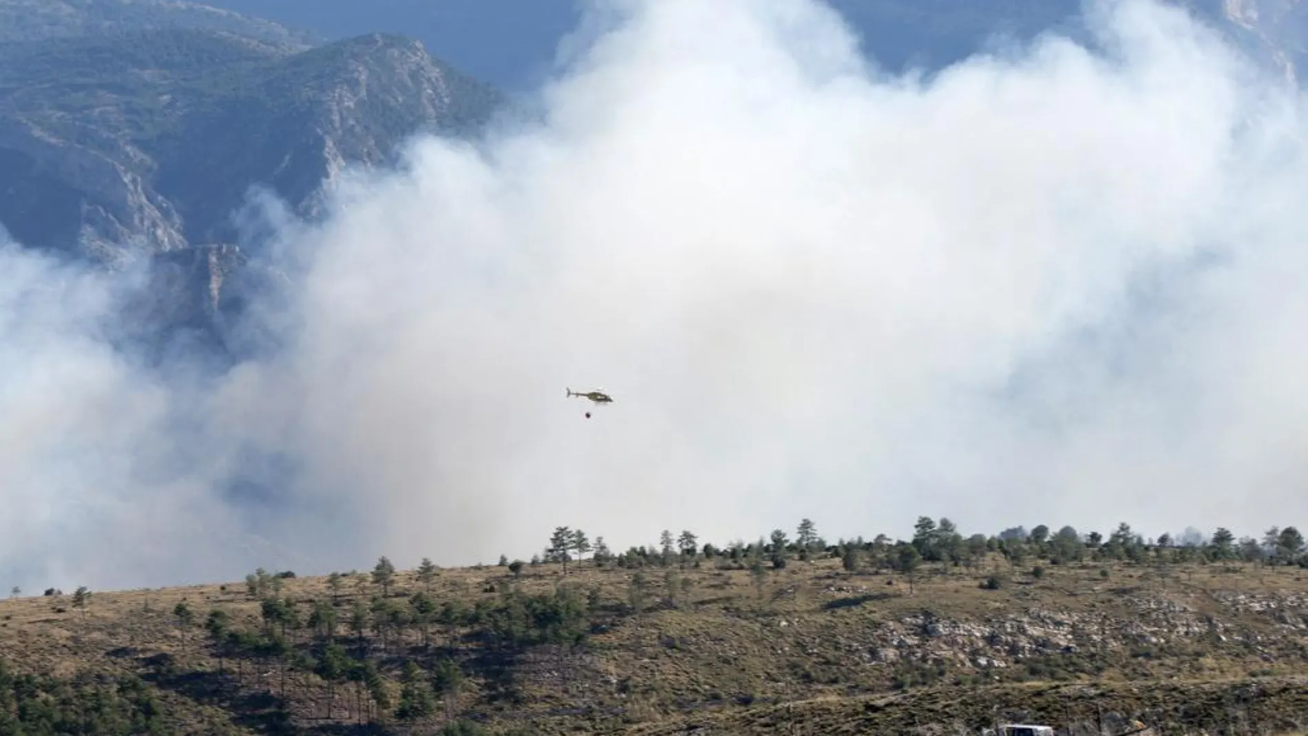 Un helicoptero trabaja en las labores de extinción del incendio originado en una zona de monte del término municipal de Ejulve (Teruel) afecta a más de un centenar de hectáreas