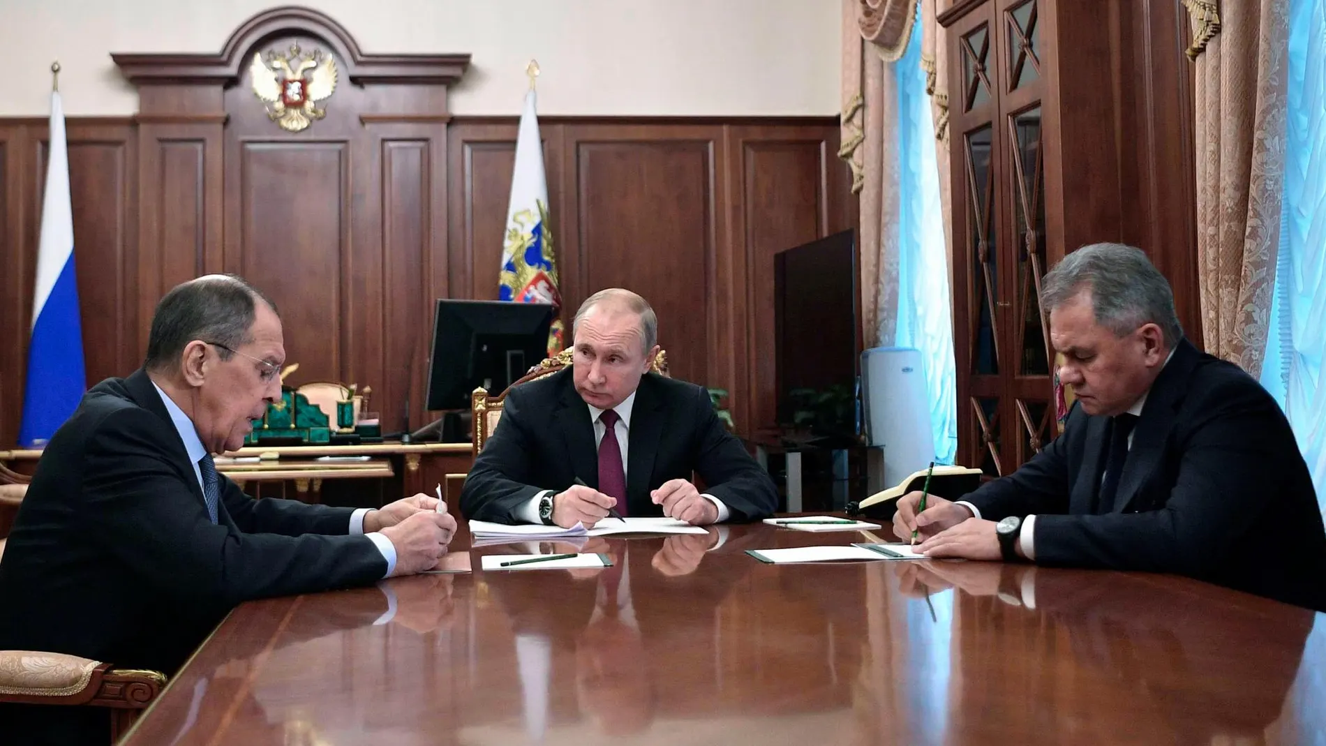 Vladimir Putin (C) durante la reunión que ha mantenido con sus ministros de Exteriores, Sergei Lavrov (L) y de Defensa, Sergei Shoigu (R).