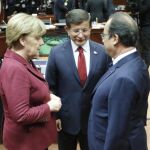 Angela Merkel y François Hollande charlan con el primer ministro turco Ahmet Davutoglu, al comienzao de la cumbre UE-Turquía hoy en Bruselas.