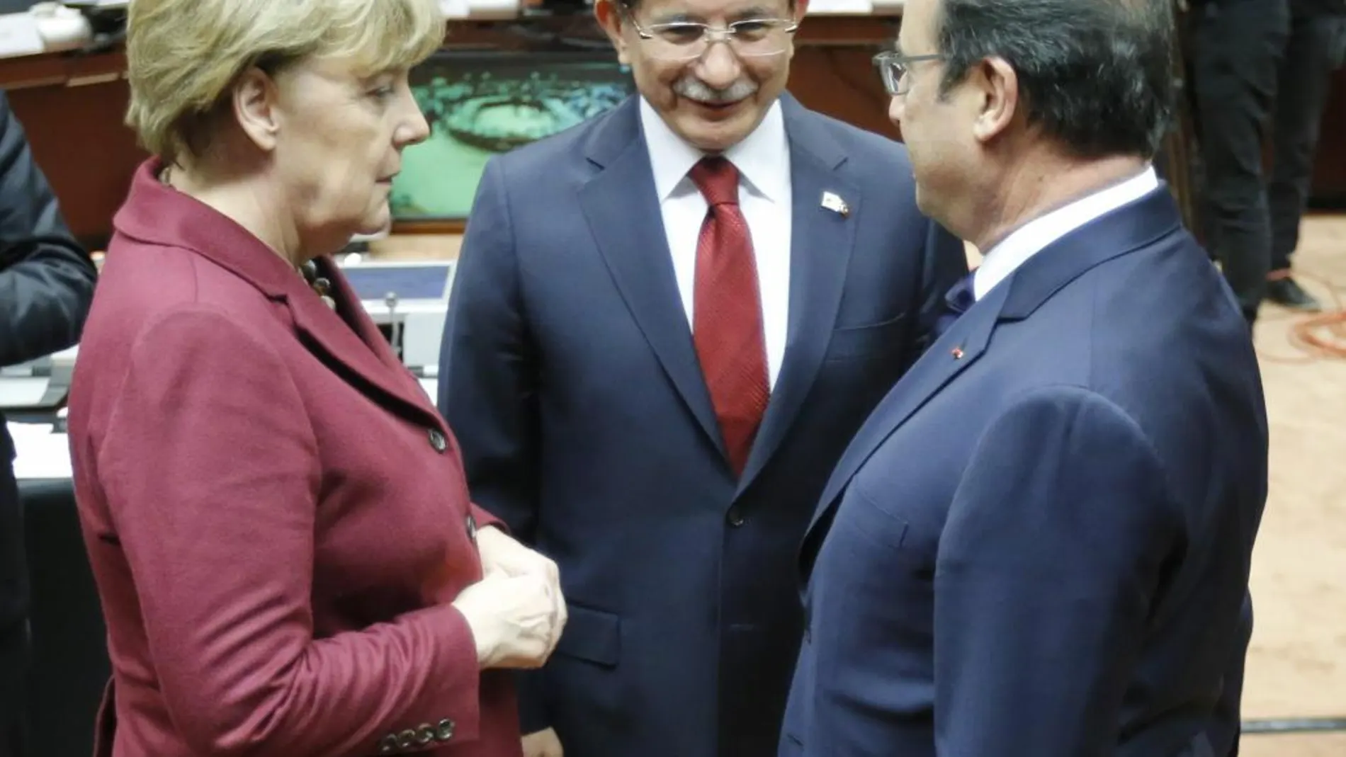 Angela Merkel y François Hollande charlan con el primer ministro turco Ahmet Davutoglu, al comienzao de la cumbre UE-Turquía hoy en Bruselas.