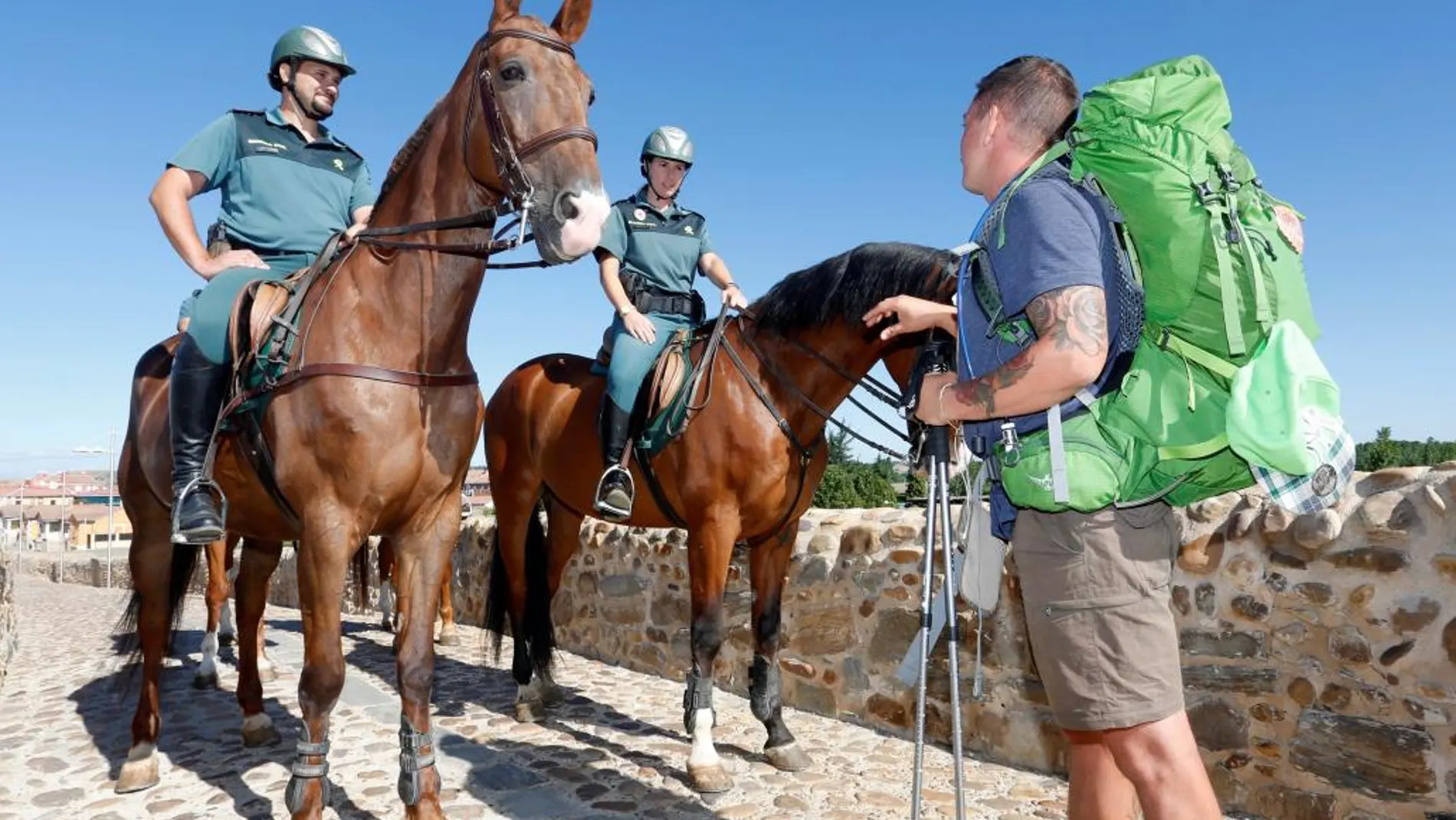 Agentes a caballo de la Guardia Civil atienden a un peregrino en el Camino de Santiago