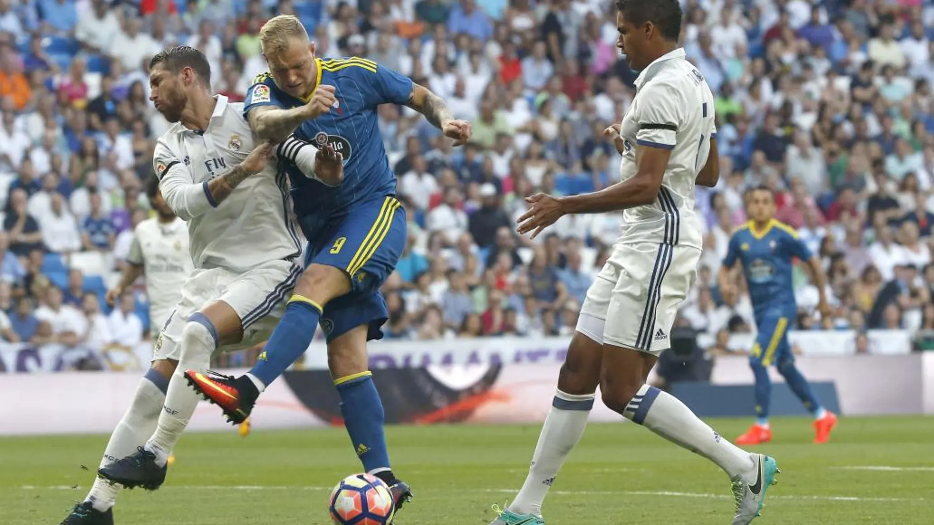 El delantero sueco del Celta de Vigo, John Guidetti, intenta golpear el balón ante los defensores del Real Madrid, Sergio Ramos y Varane