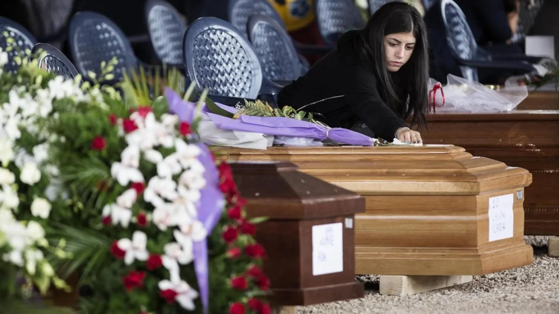 Una mujer permanece junto al ataúd de una de las víctimas del terremoto antes del inicio del funeral