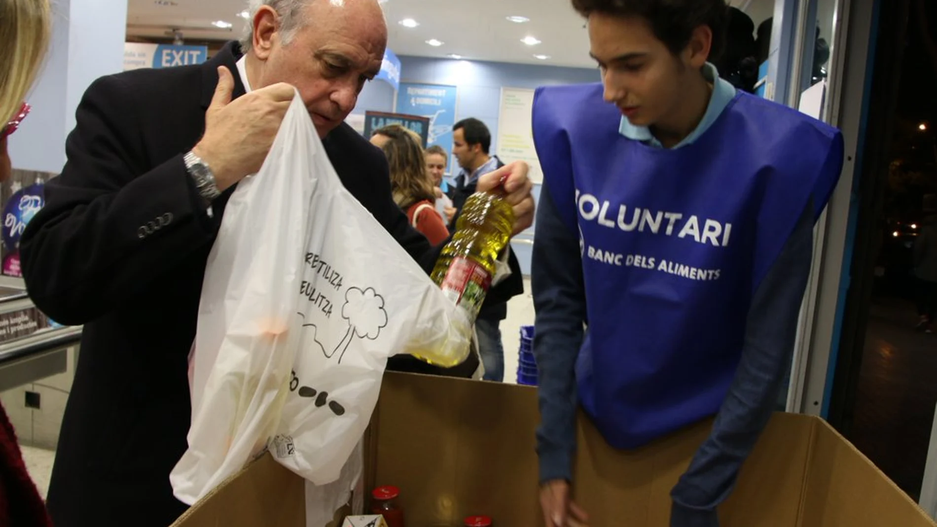 Jorge Fernández Díaz colabora con los voluntarios de la recogida solidaria del Banco de Alimentos de Cataluña.