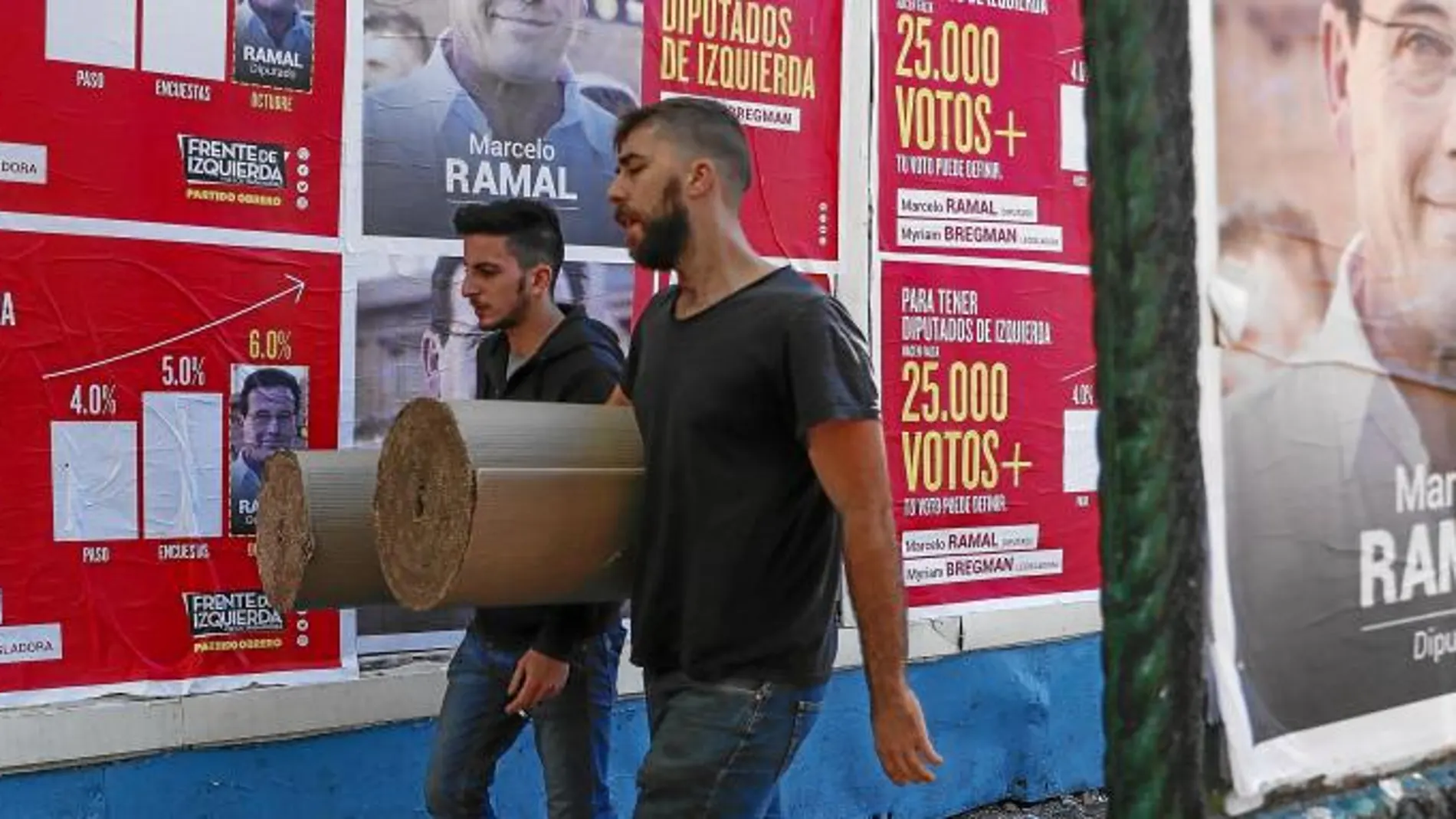 Dos porteños pasan por delante de varios carteles de campaña en una calle de la capital argentina