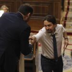 El líder de Podemos, Pablo Iglesias (d), y el portavoz del PSOE, José Luis Ábalos, se estrechan la mano durante la segunda jornada del debate.