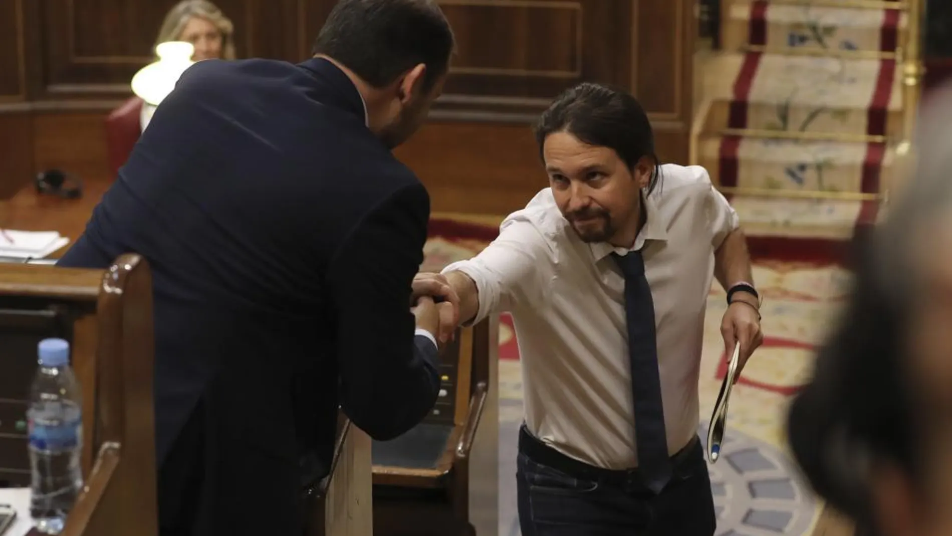 El líder de Podemos, Pablo Iglesias (d), y el portavoz del PSOE, José Luis Ábalos, se estrechan la mano durante la segunda jornada del debate.