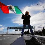 Un granjero hace ondear su bandera en el puente que une EE UU y México
