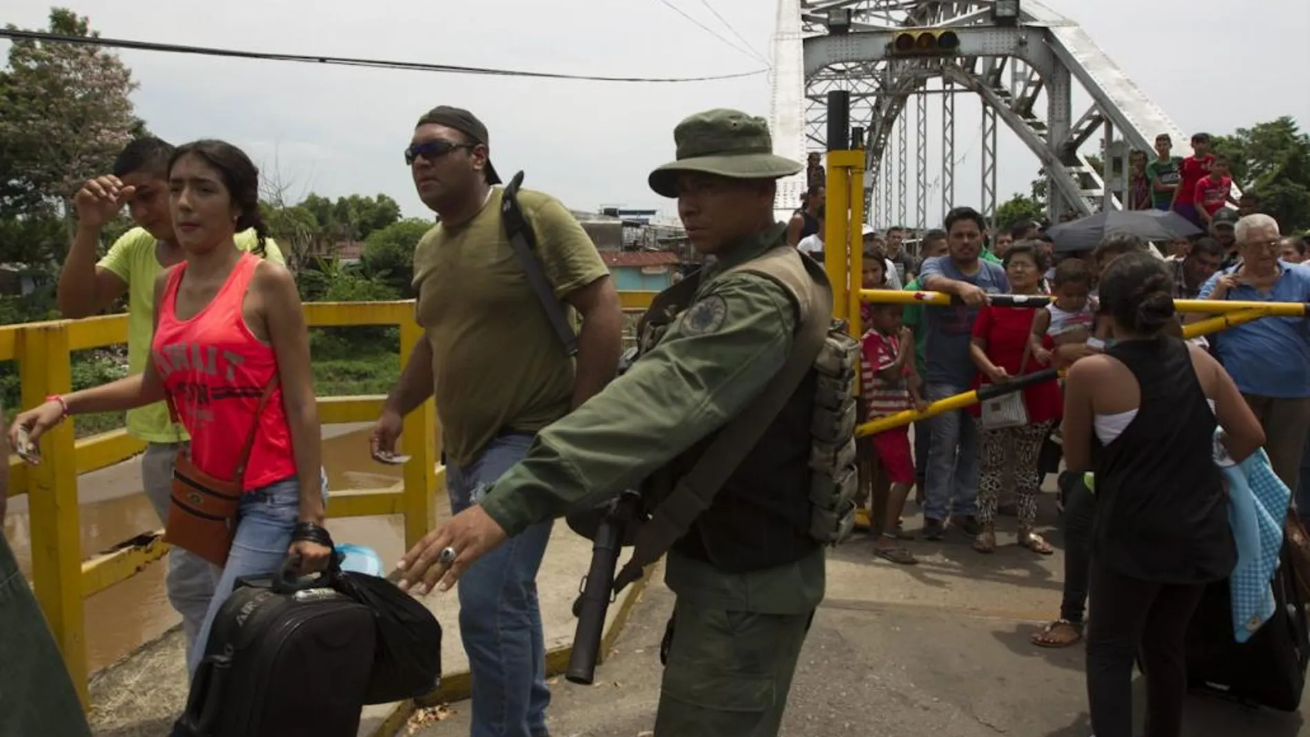 Fotografía cedida por prensa de la Vicepresidencia de Venezuela, de un miembro de la Guardia Nacional Bolivariana (GNB) da indicaciones a un grupo de ciudadanos que cruzan el puente internacional "La Union"