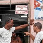 Cubanos conversan ayer en La Habana ante un cártel de la llegada del Papa Francisco