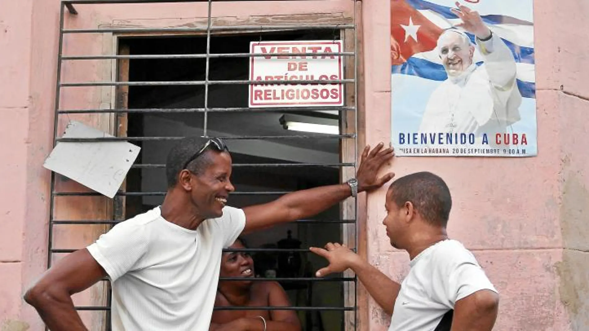Cubanos conversan ayer en La Habana ante un cártel de la llegada del Papa Francisco