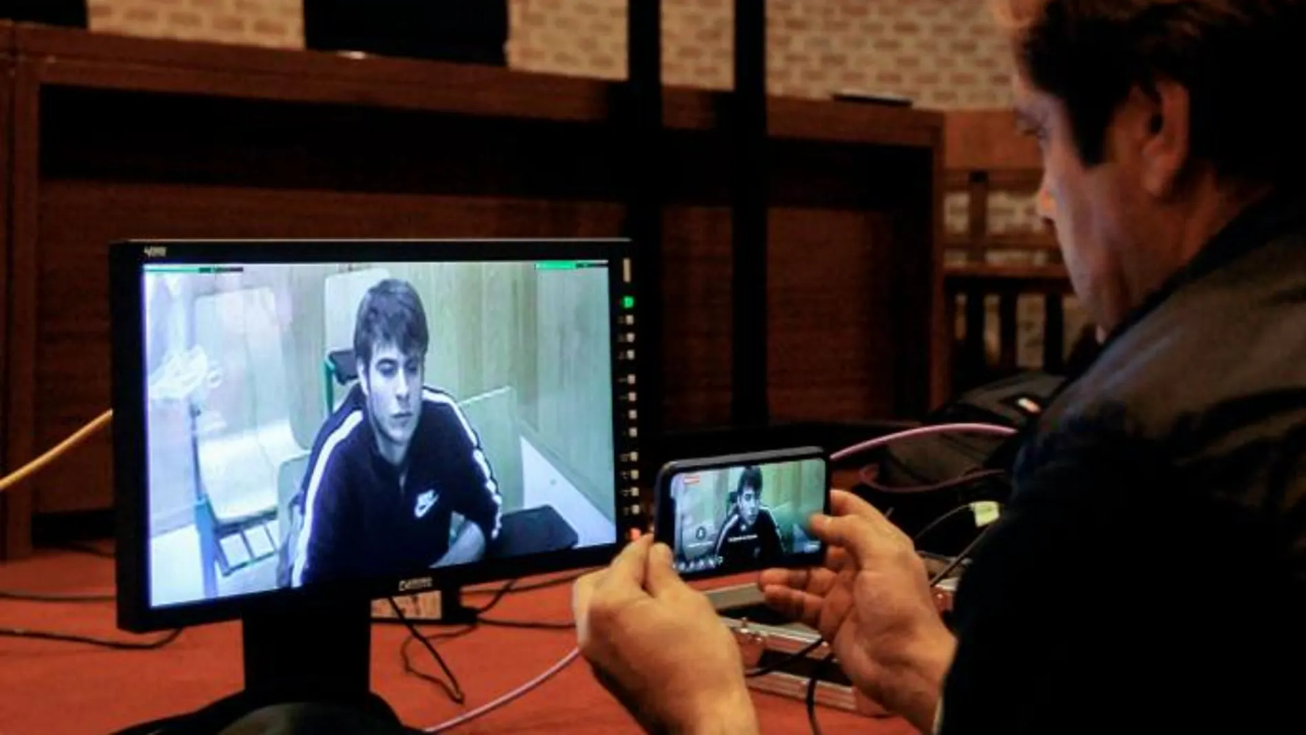 Un periodista toma imágenes de una televisión en la que se muestra a Patrick Nogueira, durante la lectura pública de la sentencia/Foto: Efe