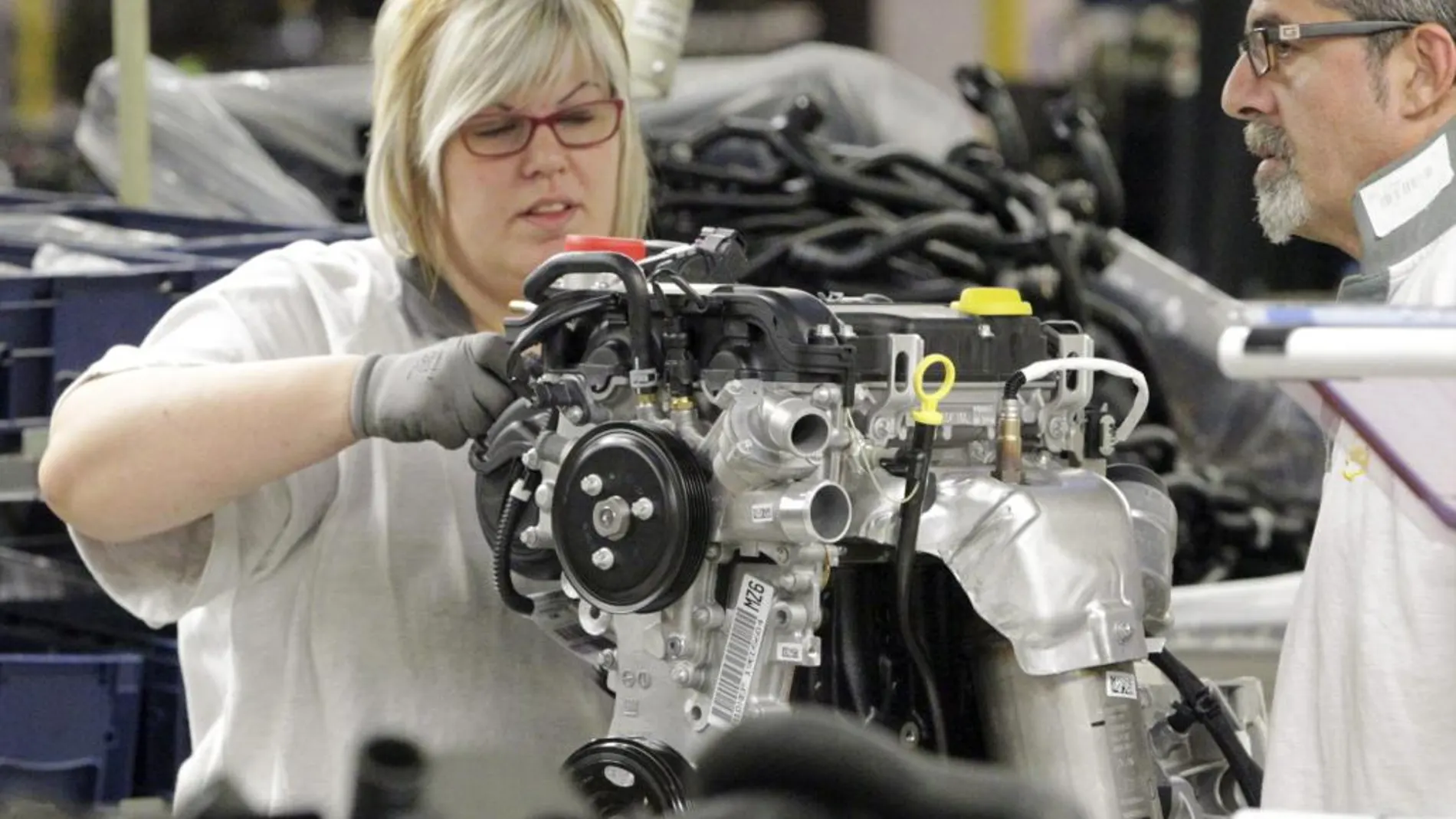 Una trabajadora de la cadena de montaje de la factoría que GM España tiene en Figueruelas (Zaragoza), coloca piezas en un motor.