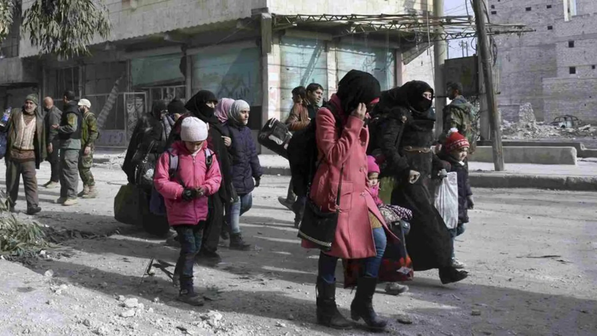 Habitantes de Alepo cargan con sus pertenencias mientras abandonan uno de los barrios que aún quedan en manos de los rebeldes