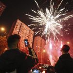 Un hombre hace una fotografía a los fuegos artificiales que lucen el cielo de Pekín durante las celebraciones del Año Nuevo Lunar.