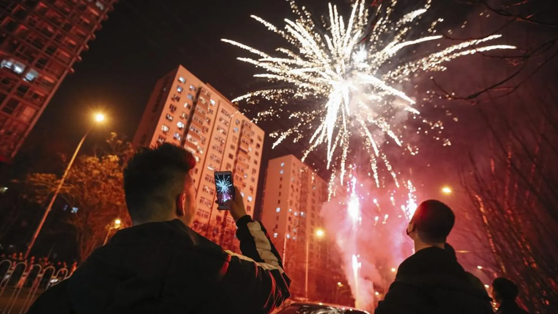 Un hombre hace una fotografía a los fuegos artificiales que lucen el cielo de Pekín durante las celebraciones del Año Nuevo Lunar.