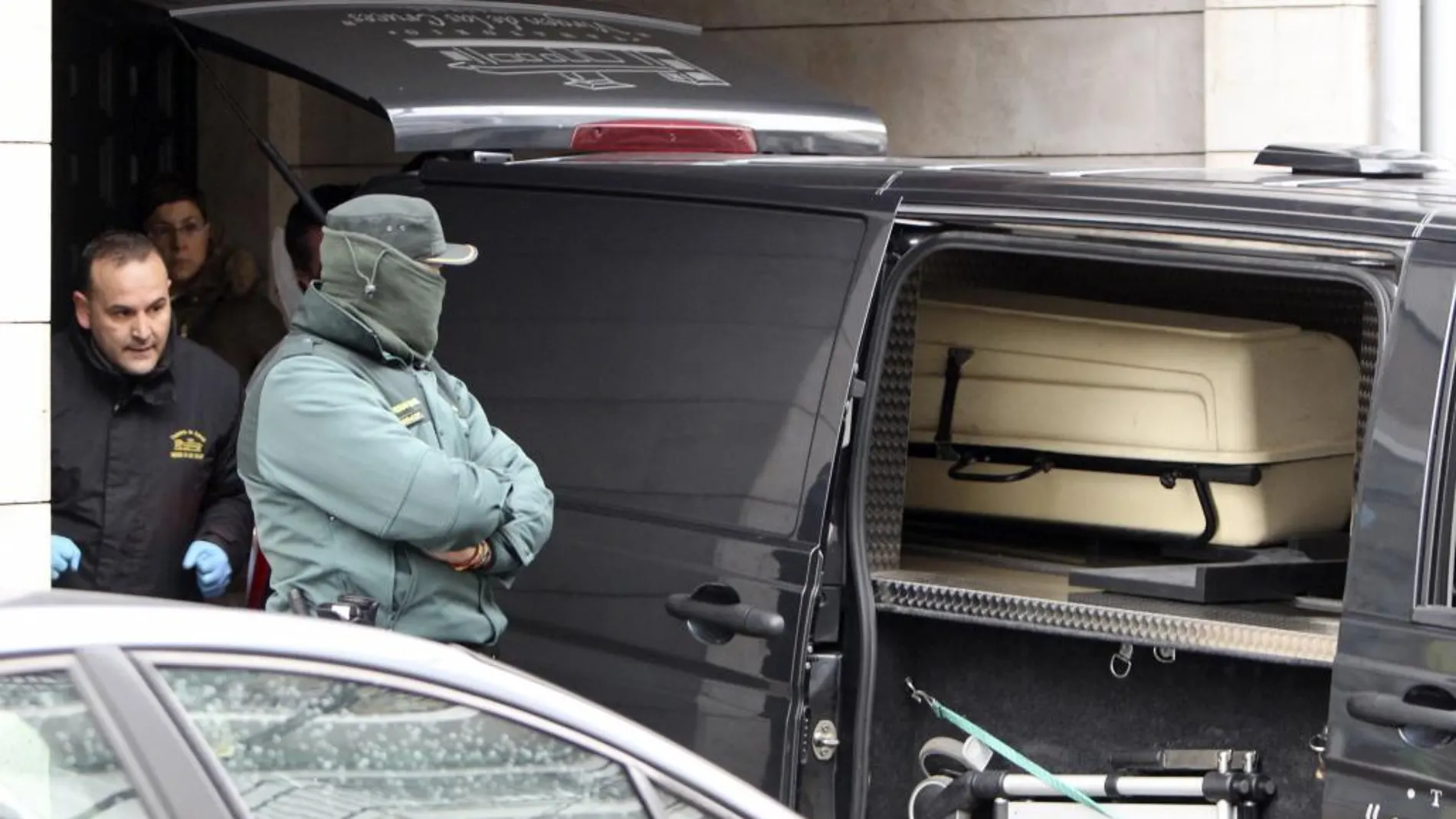 Un agente de la Guardia Civil permanece junto al furgón de los servicios funerarios, durante el traslado de los cadáveres de las dos mujeres asesinadas hoy a cuchilladas