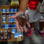Un vendedor sostiene una bolsa de café en un puesto de venta informal en una calle de Caracas (Venezuela)