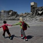 Dos niños sirios caminan junto a las ruinas en una zona de la ciudad de Raqa, destruida durante la batalla contra el Estados Islámico