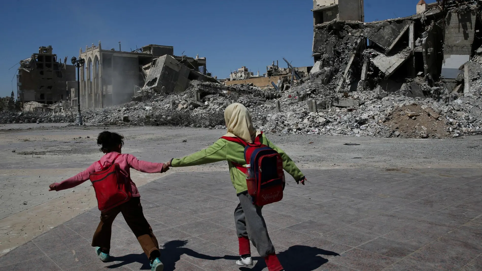 Dos niños sirios caminan junto a las ruinas en una zona de la ciudad de Raqa, destruida durante la batalla contra el Estados Islámico