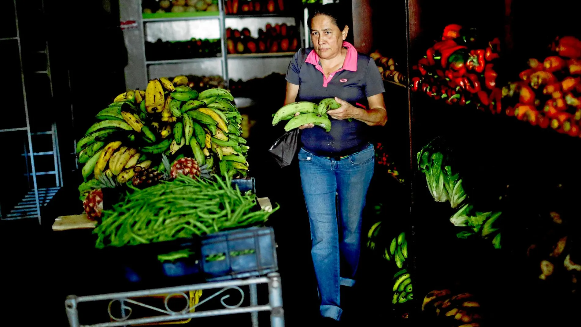 Una mujer camina a oscuras en una frutería de Caracas en medio del apagón