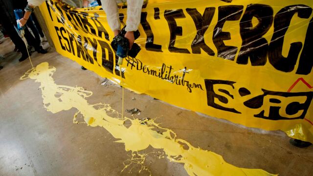 Jóvenes antililitaristas vertieron pintura amarilla en protesta por la situación de un estand del Ejército en el salón de la juventud Expojove de Girona, después de que un juez haya anulado la prohibición impuesta por la institución que acoge esta cita, Fira de Girona, en aplicación de su código ético.