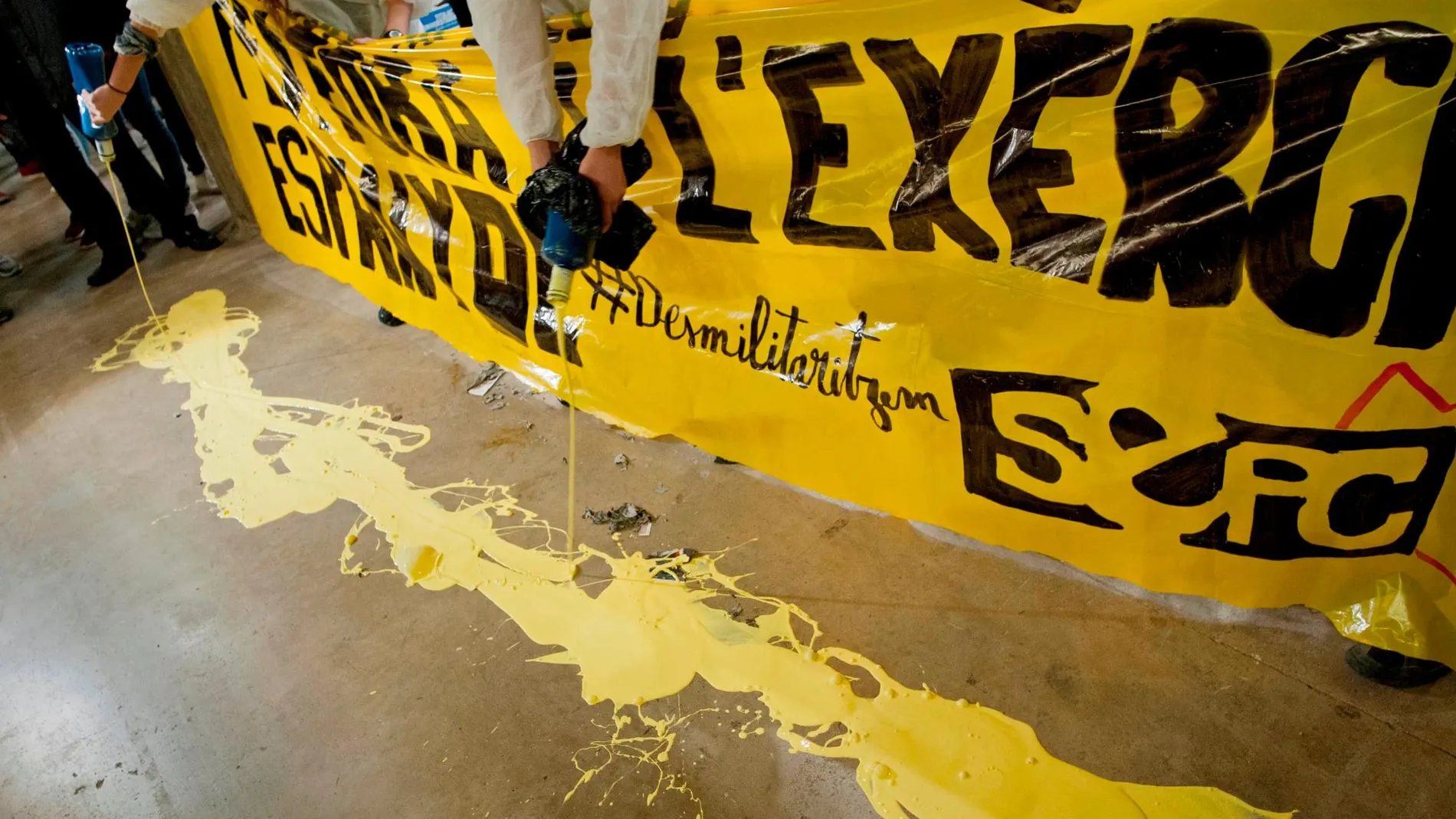 Jóvenes antililitaristas vertieron pintura amarilla en protesta por la situación de un estand del Ejército en el salón de la juventud Expojove de Girona, después de que un juez haya anulado la prohibición impuesta por la institución que acoge esta cita, Fira de Girona, en aplicación de su código ético.