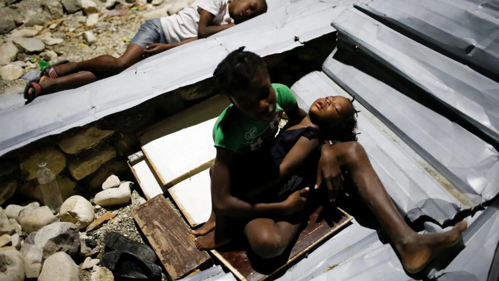 Varios niños duermen sobre los restos del tejado de su escuela