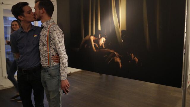 Jon y Alex, pareja que fue fotografiada por el fotógrafo danés, Mads Nissen en 2014 en san petesbrugo, se besan junto a la fotografía en la muestra de World Press Photo, en San Petesburgo en septiembrede 2015