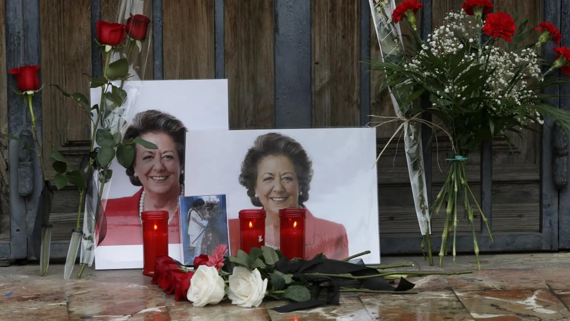 Una persona se para ante unas fotografías y flores colocadas ante el Ayuntamiento de Valencia en memoria de Rita Barberá.