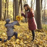 Imagen de un hijo creando un ramo con las hojas caídas de los árboles para su madre