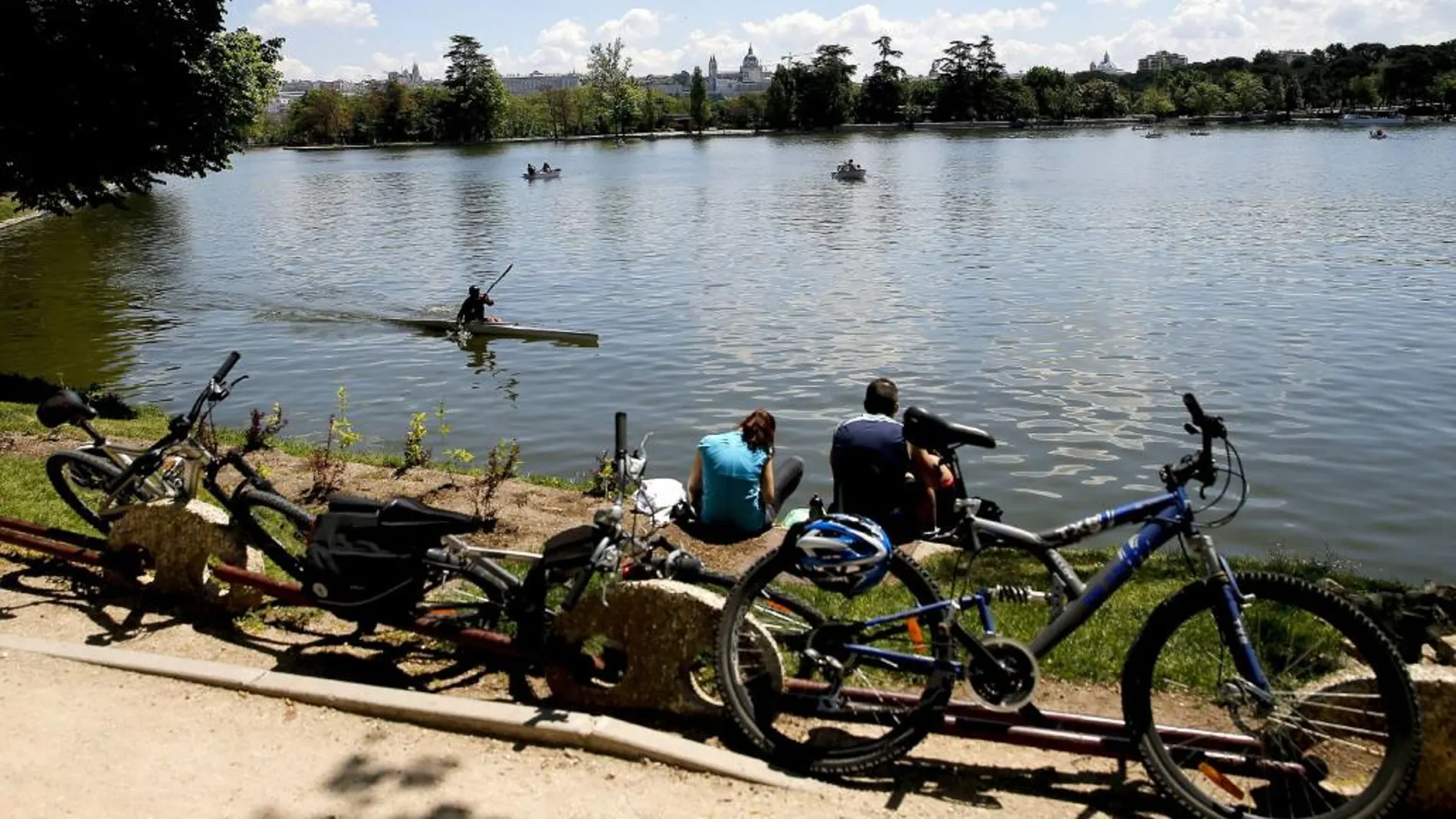 Varias personas disfrutan del buen tiempo junto al lago de la Casa de Campo de Madrid.