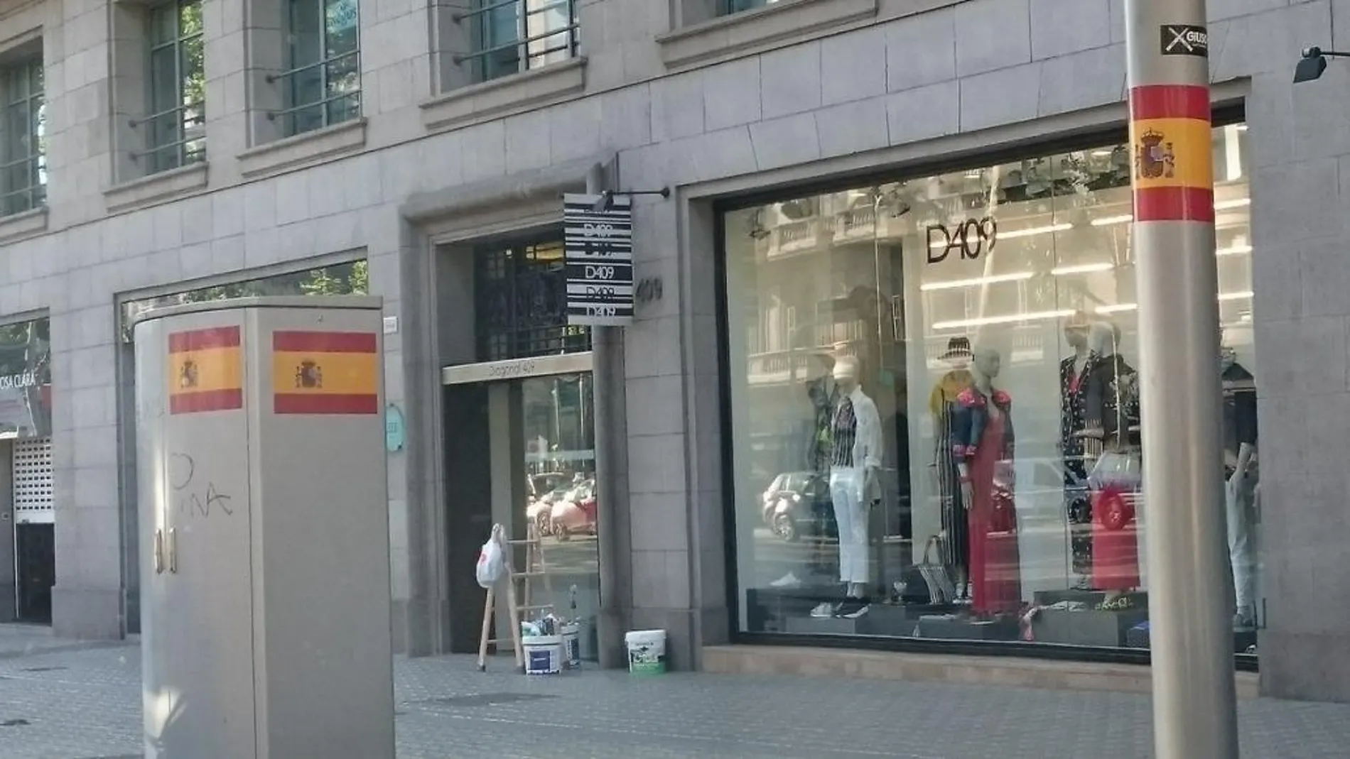 Centenares de grandes pegatinas que reproducen la bandera española han aparecido esta mañana en elementos del mobiliario urbano y en edificios de Barcelona