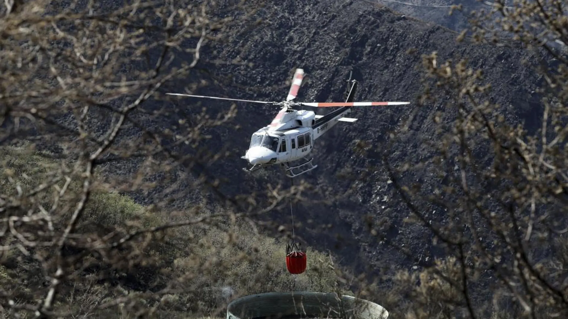 Un helicóptero recoge agua para ayudar a extinguir un incendio en León
