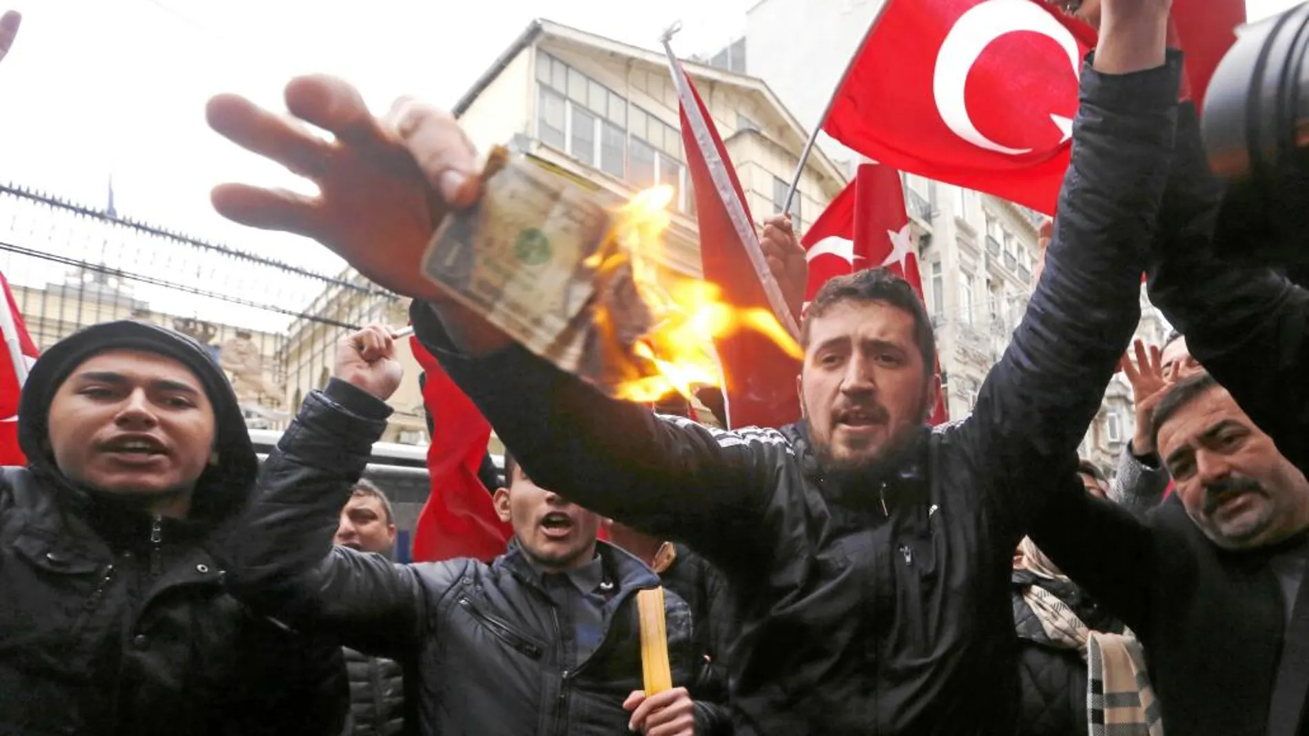 Partidarios de Erdogan queman un billete de dólar americano en una protesta contra Holanda en Estambul