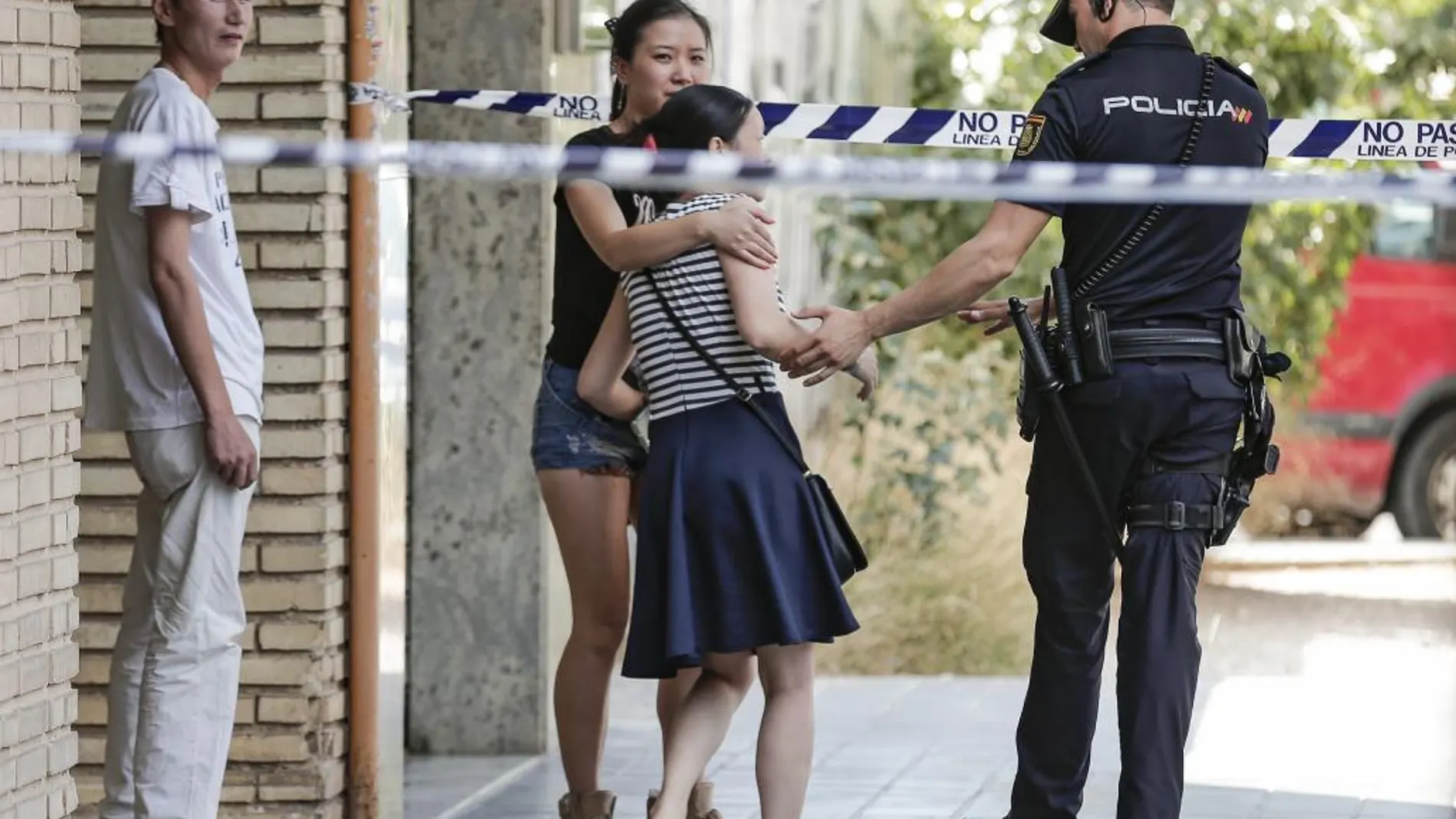 Una joven consuela a una mujer a la puerta del número 21 de la calle Villarroya de Valencia donde se han encontrado los cadáveres acuchillados