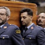 Tres compañeros sostienen el féretro de uno de los militares fallecidos