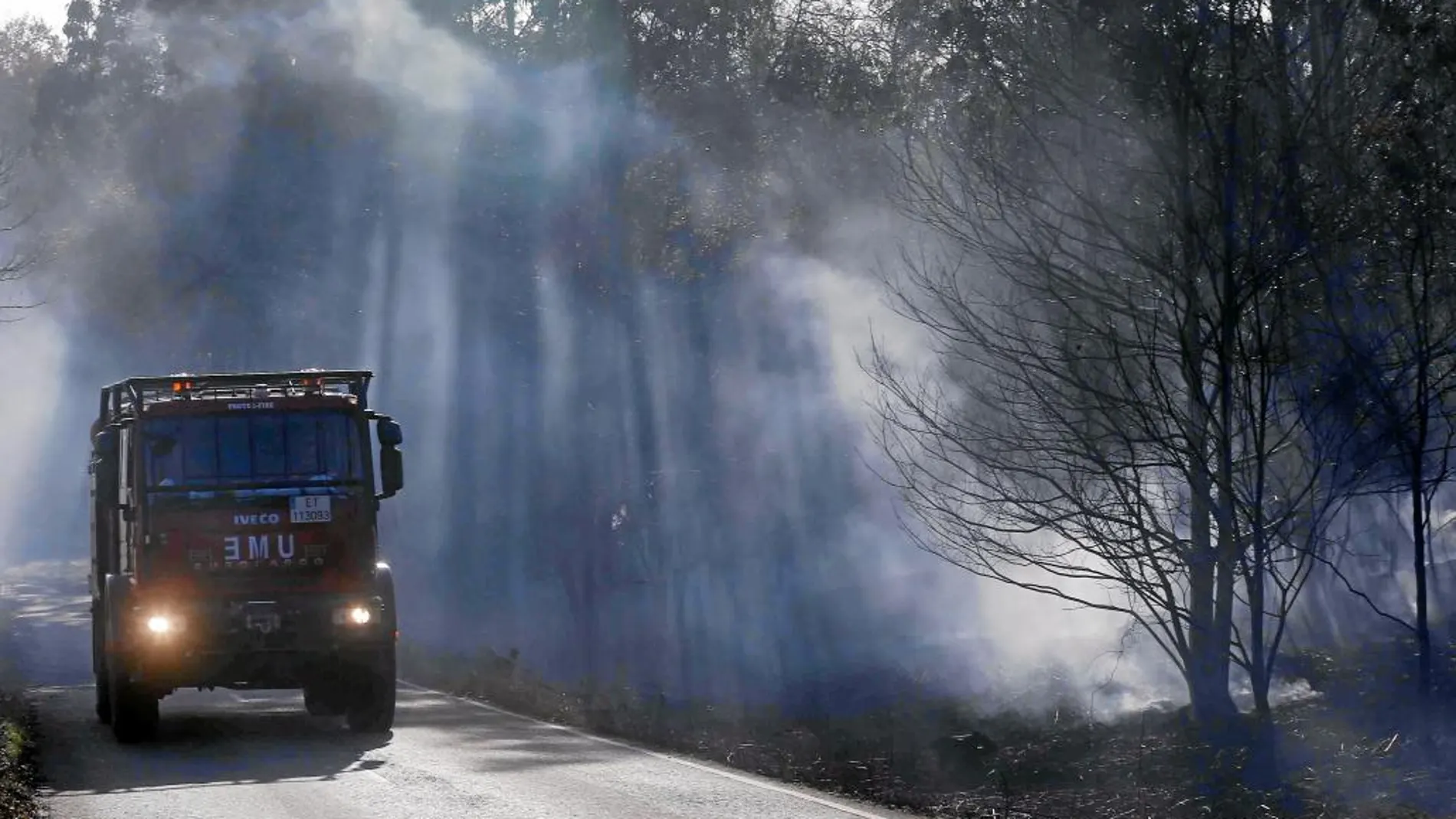 Un vehículo de la Unidad Militar de Emergencias transita por una carretera cerca de una zona incendiada, en Asturias