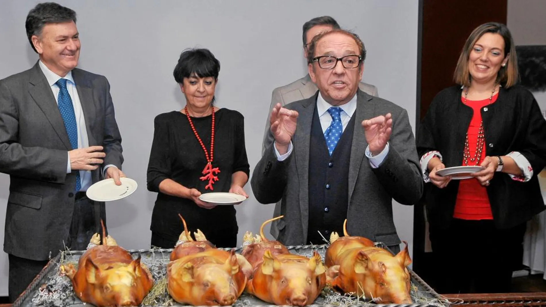 El presidente de Procose, José María Ruiz, explica como trinchar un cochinillo a Milagros Marcos, Vázquez y De Santos
