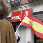 Una persona ondea una bandera española en la sede central del PSOE en la calle Ferraz de Madrid