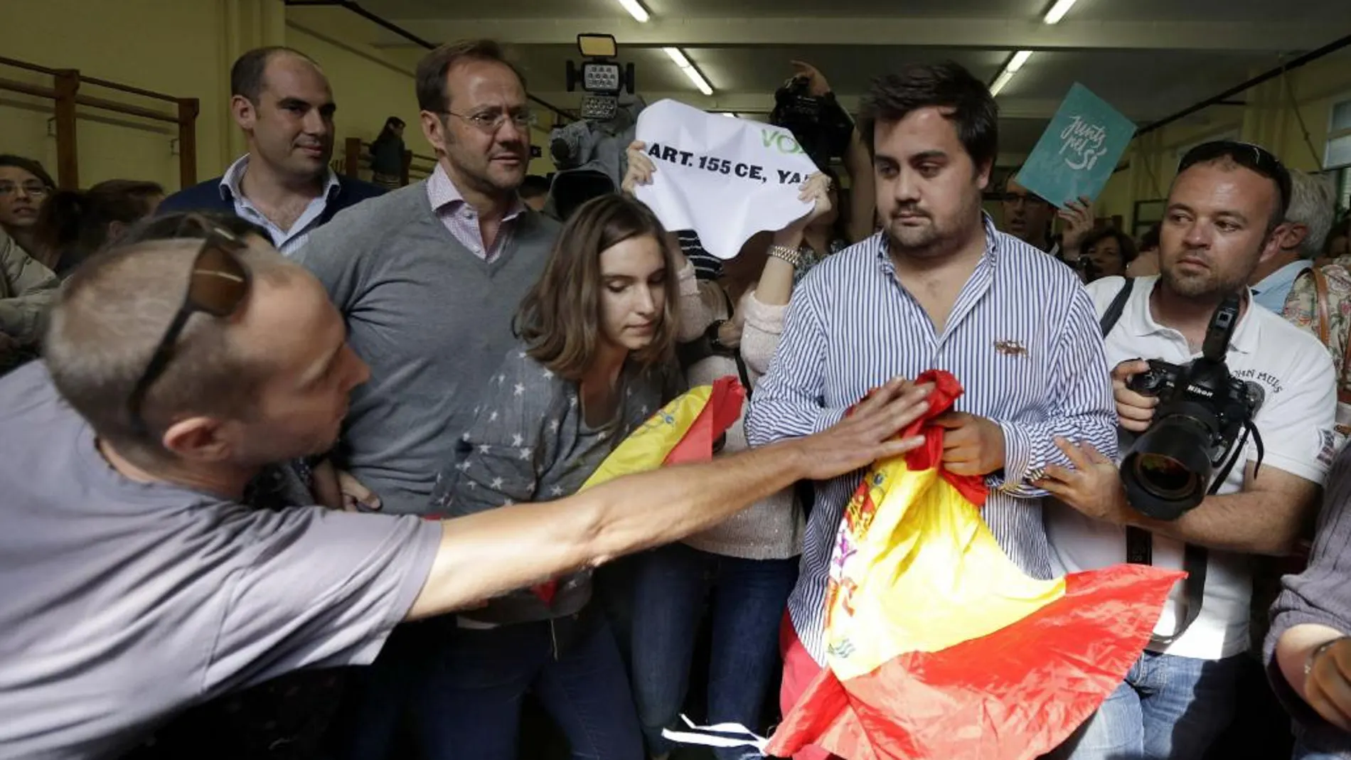 Una persona trata de arrebatar una bandera a un miembro de VOX en el colegio donde acudió a votar Artur Mas