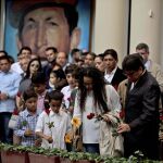 Un grupo de venezolanos ponen flores en su tumba durante el memorial por el aniversario de su muerte