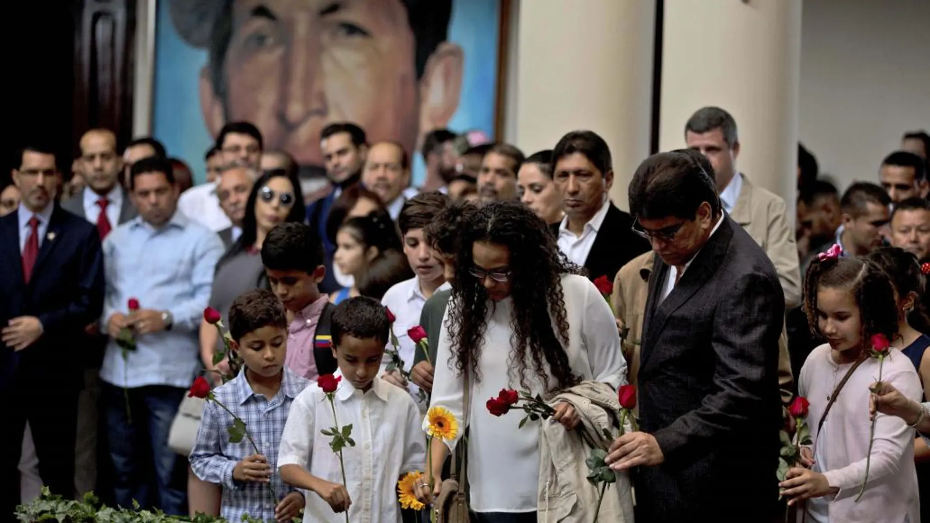Un grupo de venezolanos ponen flores en su tumba durante el memorial por el aniversario de su muerte
