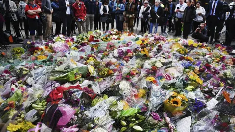 Varias personas contemplan las flores colocadas como homenaje a las víctimas del atentado terrorista d