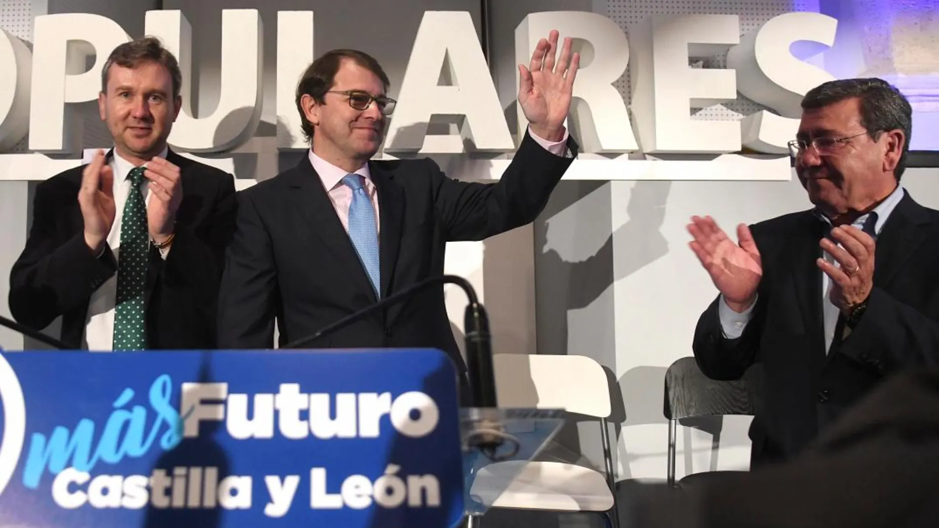 El presidente del PP de Castilla y León, Alfonso Fernández Mañueco, saluda a los asistentes, junto al alcalde de Burgos, Javier Lacalle, y el presidente provincial, César Rico