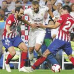 Benzema se intenta llevar el balón ante los rojiblancos Juanfran y Giménez