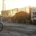 Una moto pasa frente a uno de los camiones de ayuda humanitaria que fueron calcinados cerca de Alepo